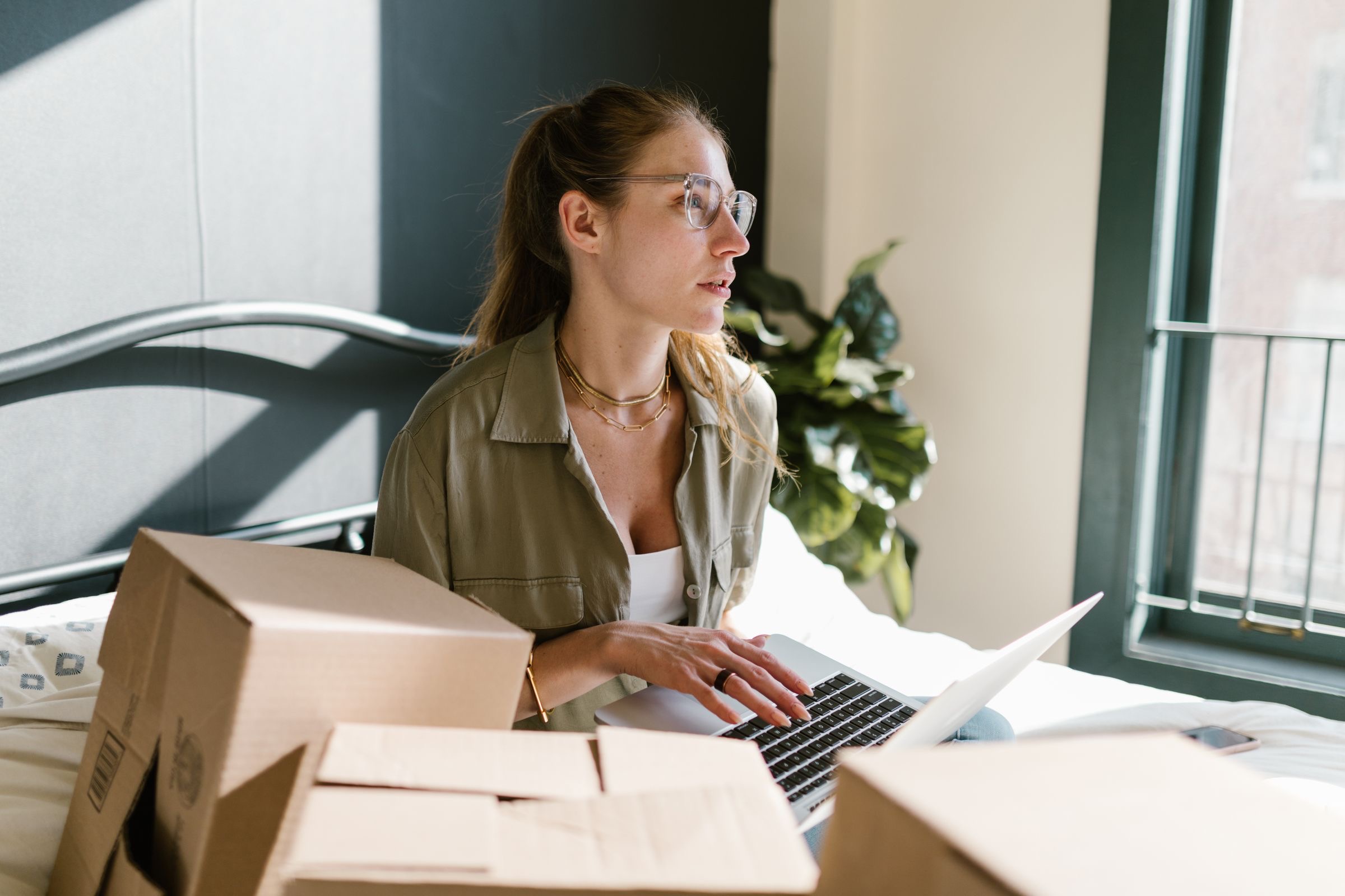A founder working at a laptop in a half-furnished apartment, moving boxes beside the desk