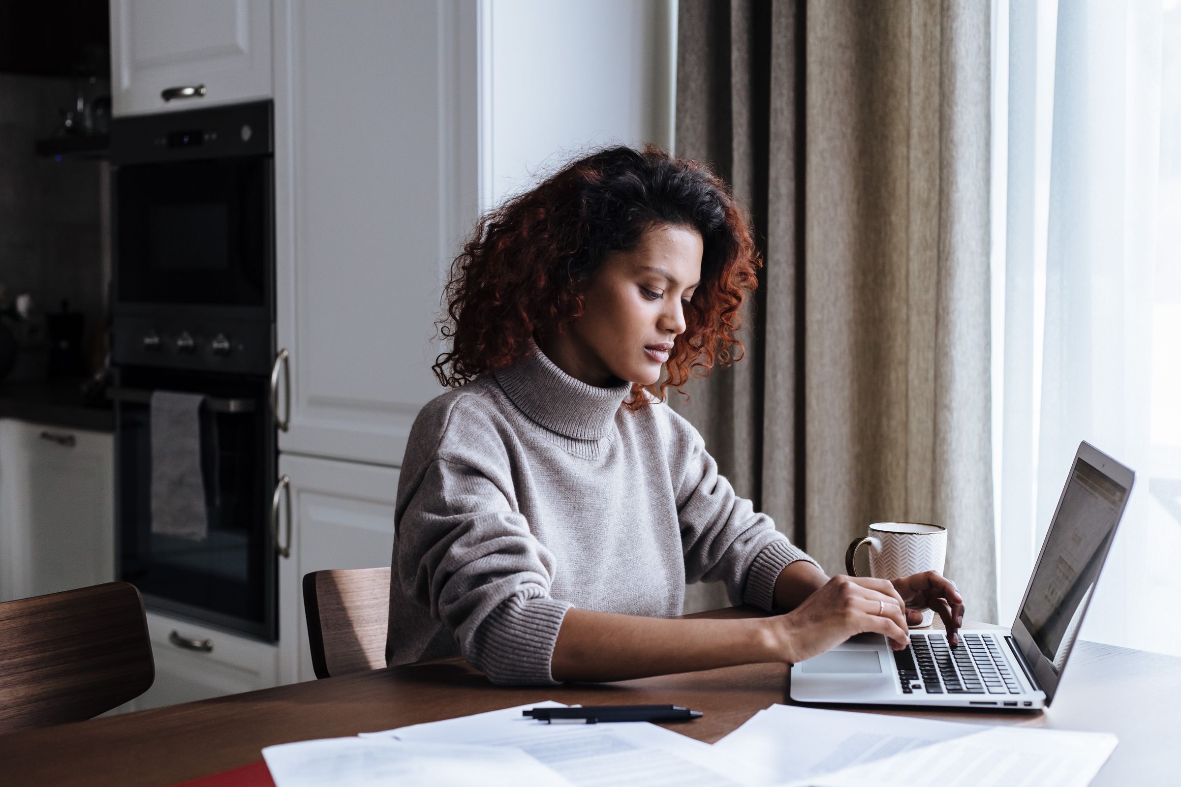 A founder at a kitchen table working through tax paperwork on a laptop