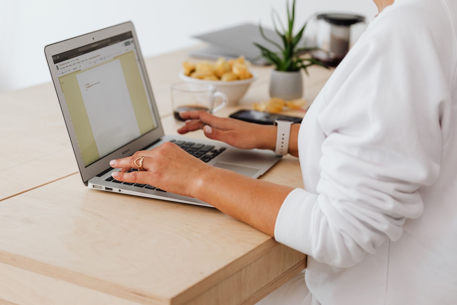 A small business owner checking a printed invoice beside a laptop showing a website footer