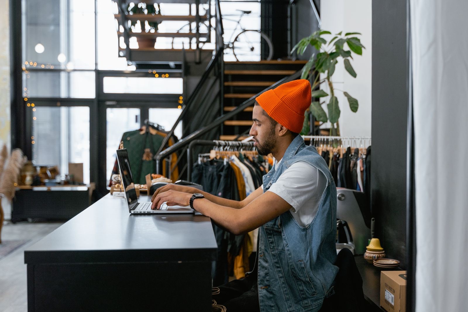 A shop owner at the counter of a small business, working on a laptop