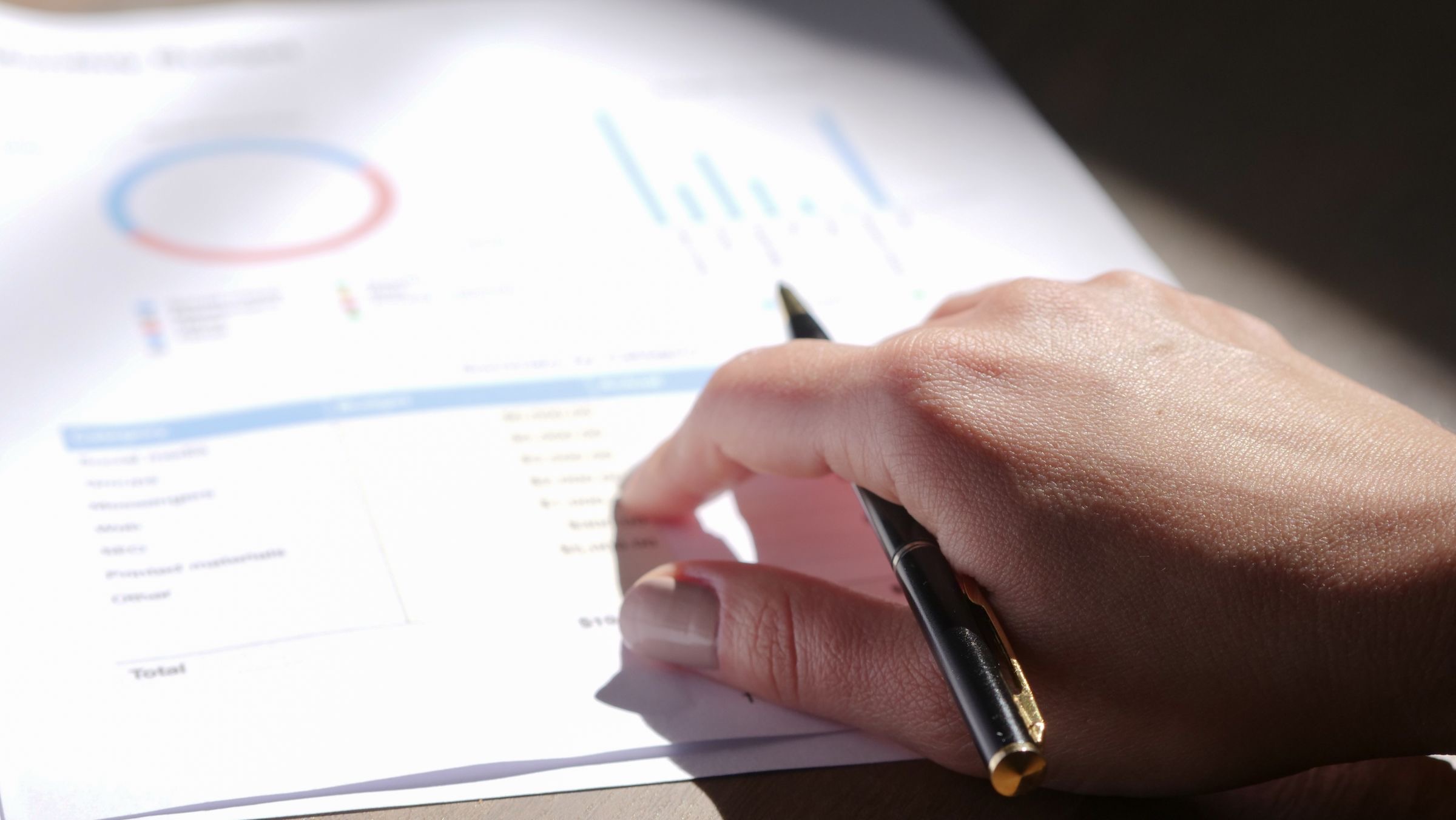 A person reading through company papers at a desk before signing