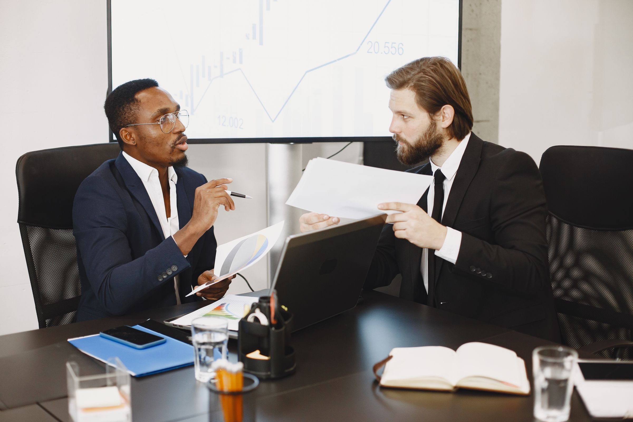 Two business partners at one table going through papers and a laptop in a bright Dutch interior