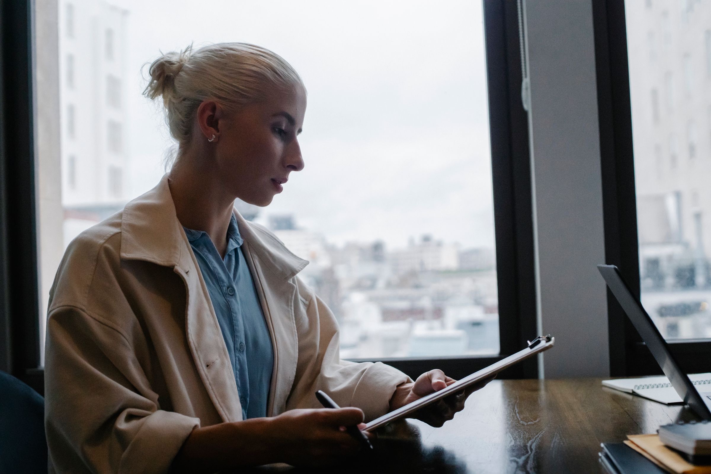 A founder reading on a tablet by a tall window
