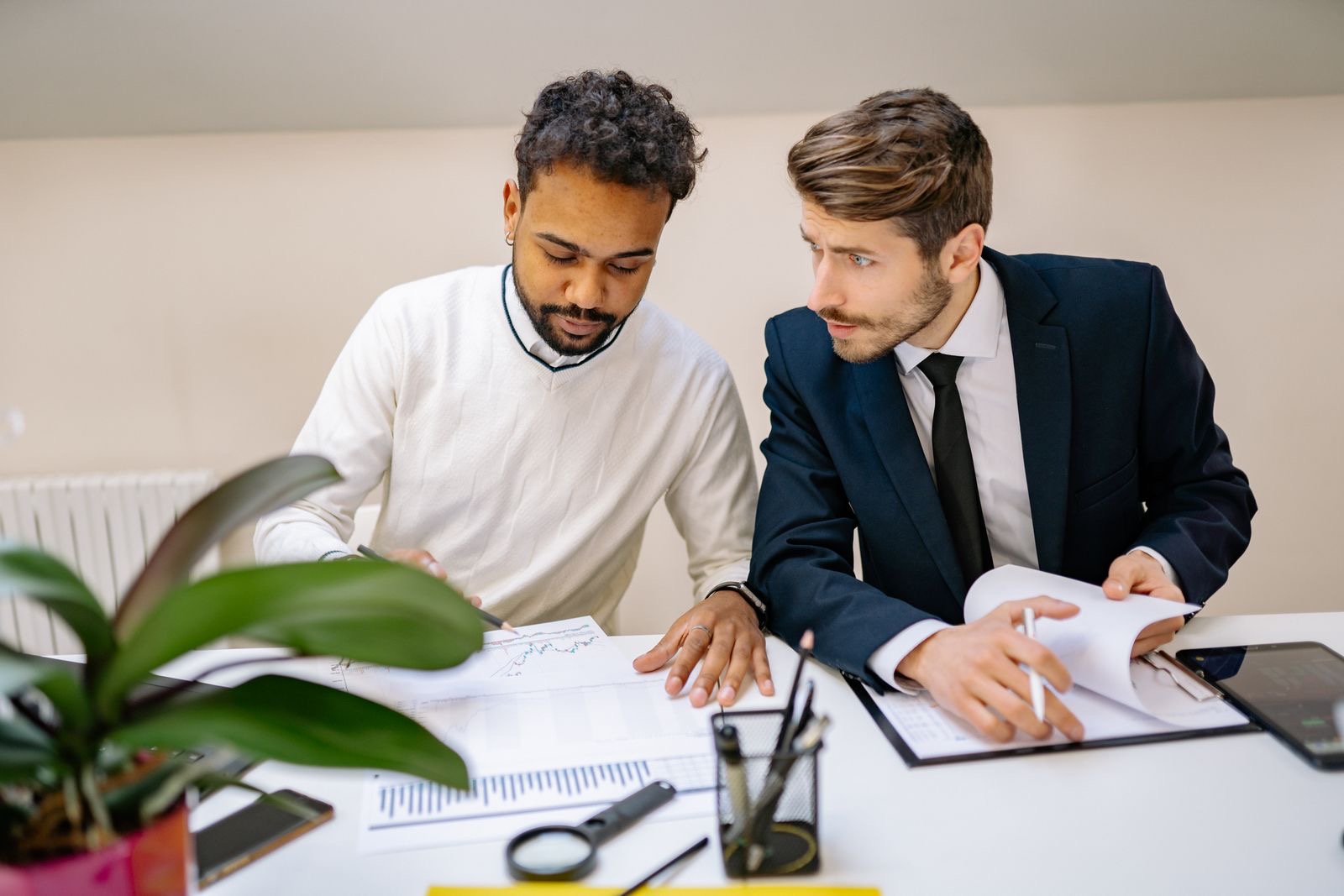 Two people going through a small stack of papers across a desk