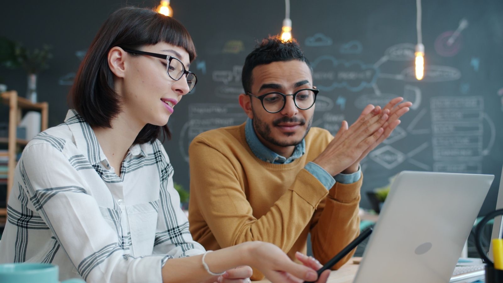 Two people at a table going through a printed business plan and a notebook